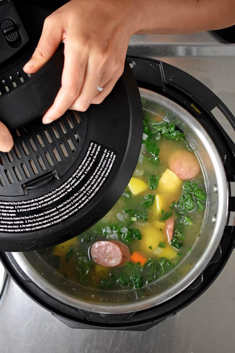 A person enjoying a bowl of pressure cooker sausage and kale soup.