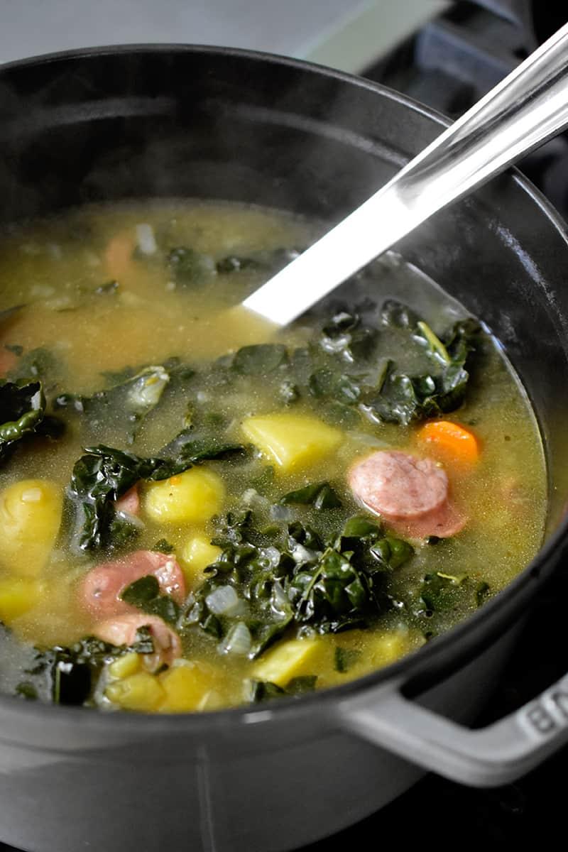 Close-up shot of a bowl of steaming pressure cooker sausage and kale soup.