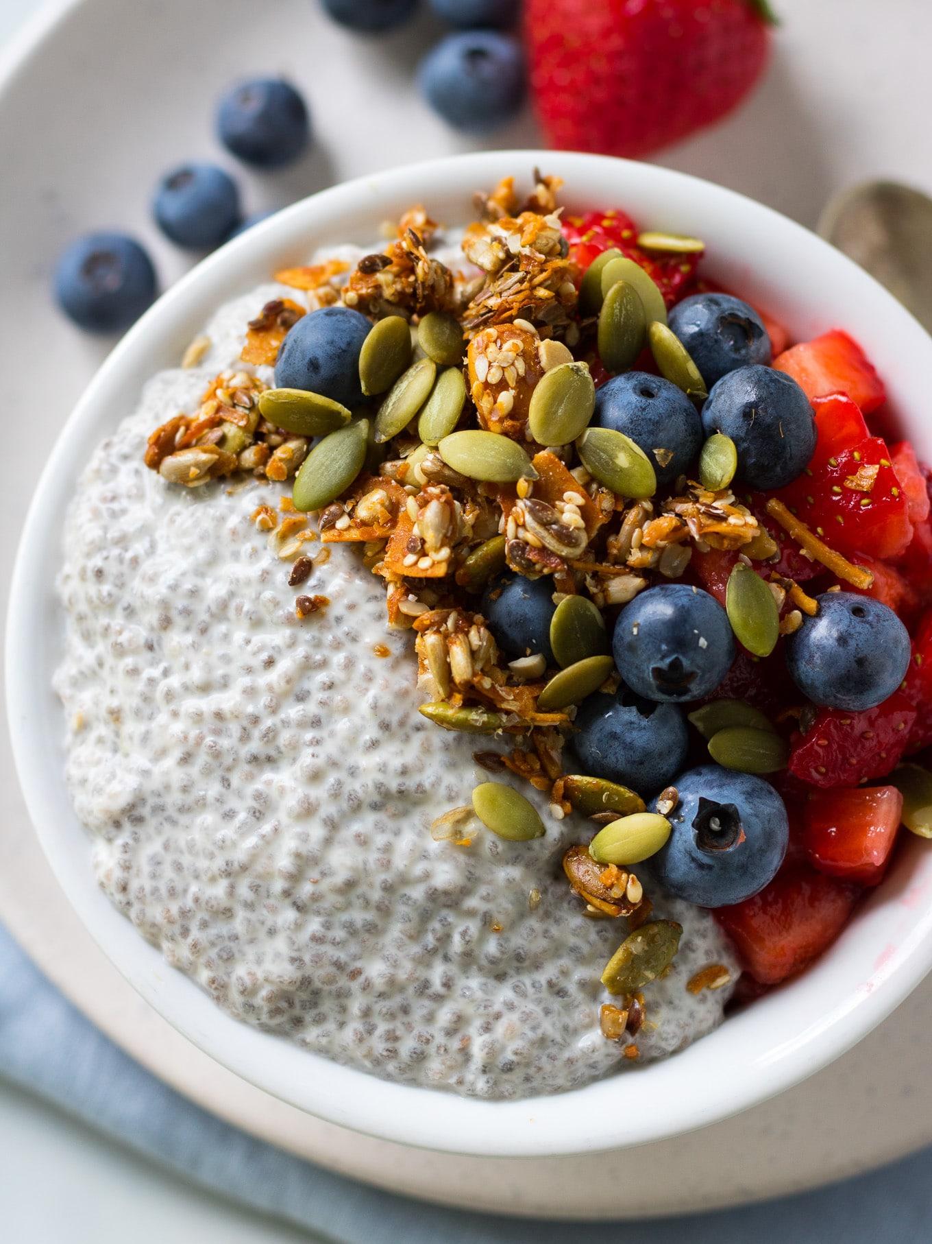 carrot greens chia pudding being served with fresh berries and nuts as toppings
