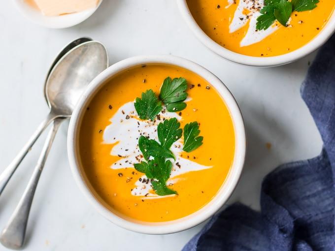 bowl of pumpkin soup garnished with toasted coconut and ginger