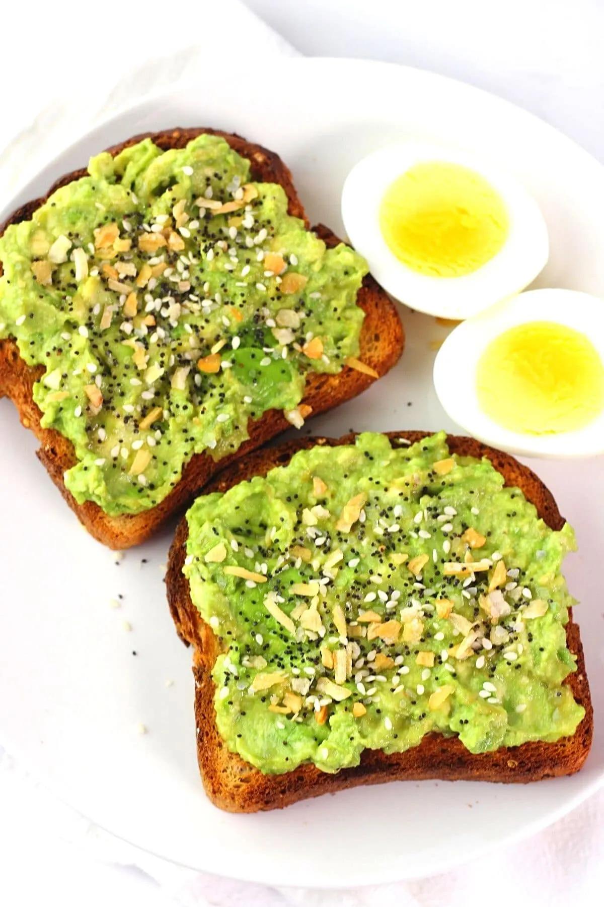 A plate of avocado toast garnished with everything bagel seasoning and a small bowl of salsa.