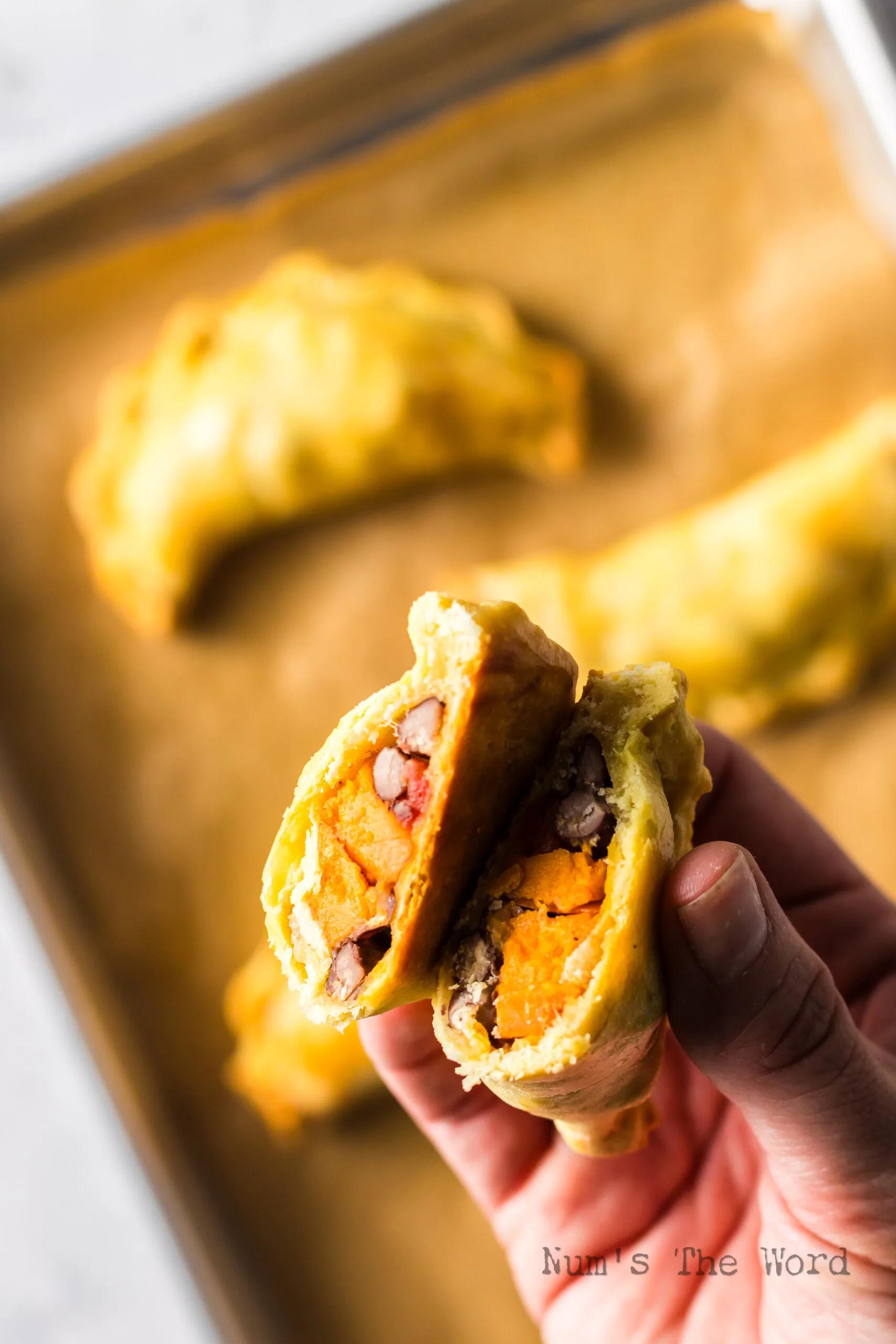 side view of an empanada being cut open to reveal the creamy potato filling