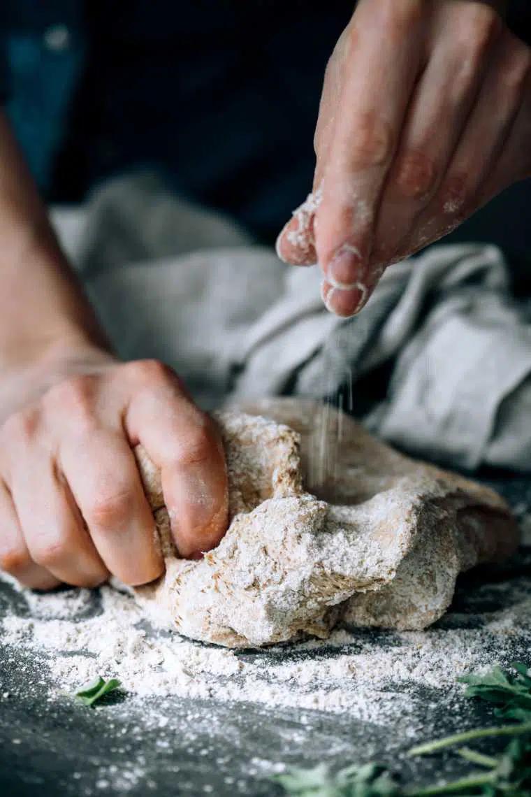 a person assembling pizza rolls on a floured surface