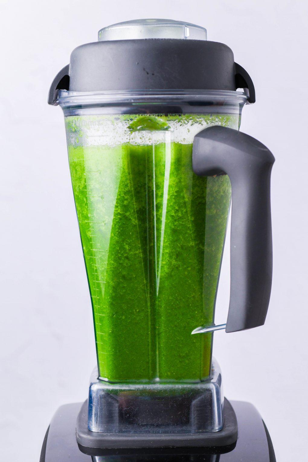 a close-up shot of a blender with the peachy green smoothie being blended, showcasing the vibrant colors and creamy texture
