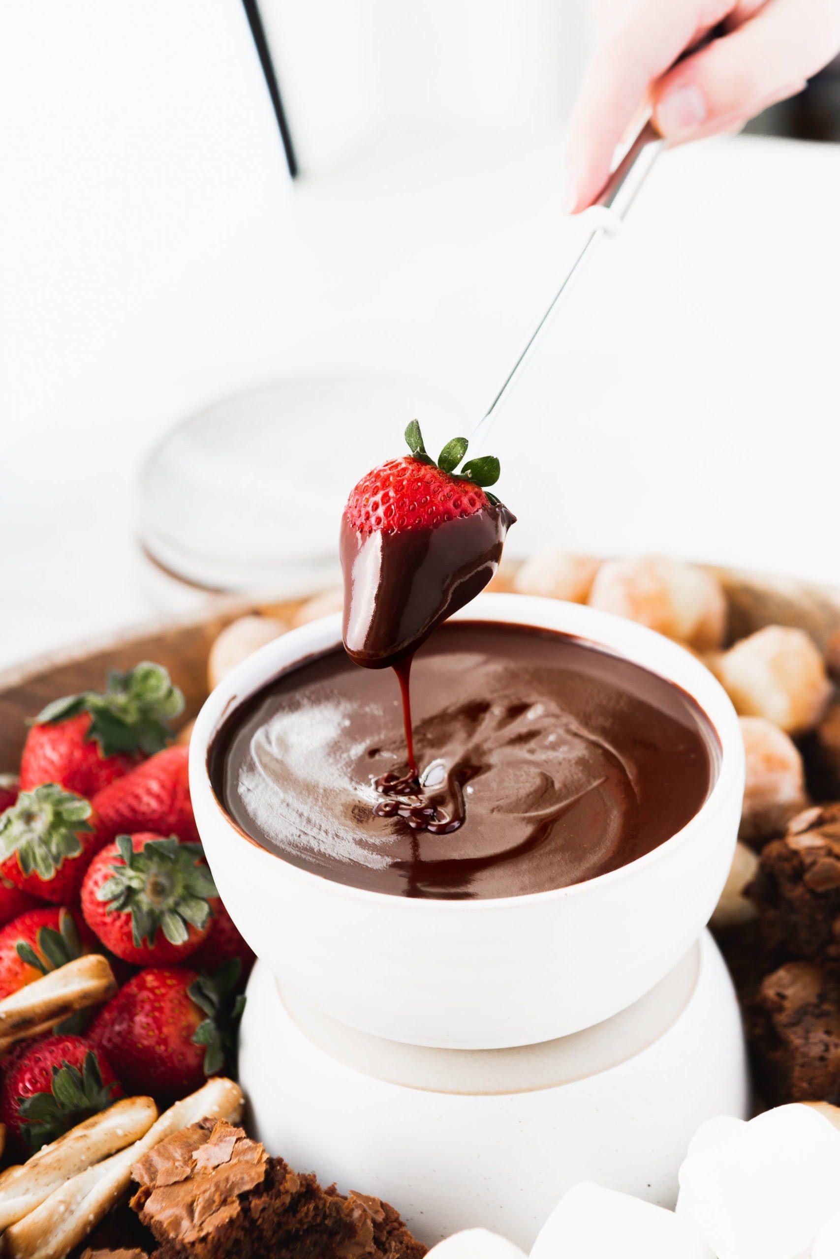 overhead view of a person dipping a strawberry into chocolate fondue
