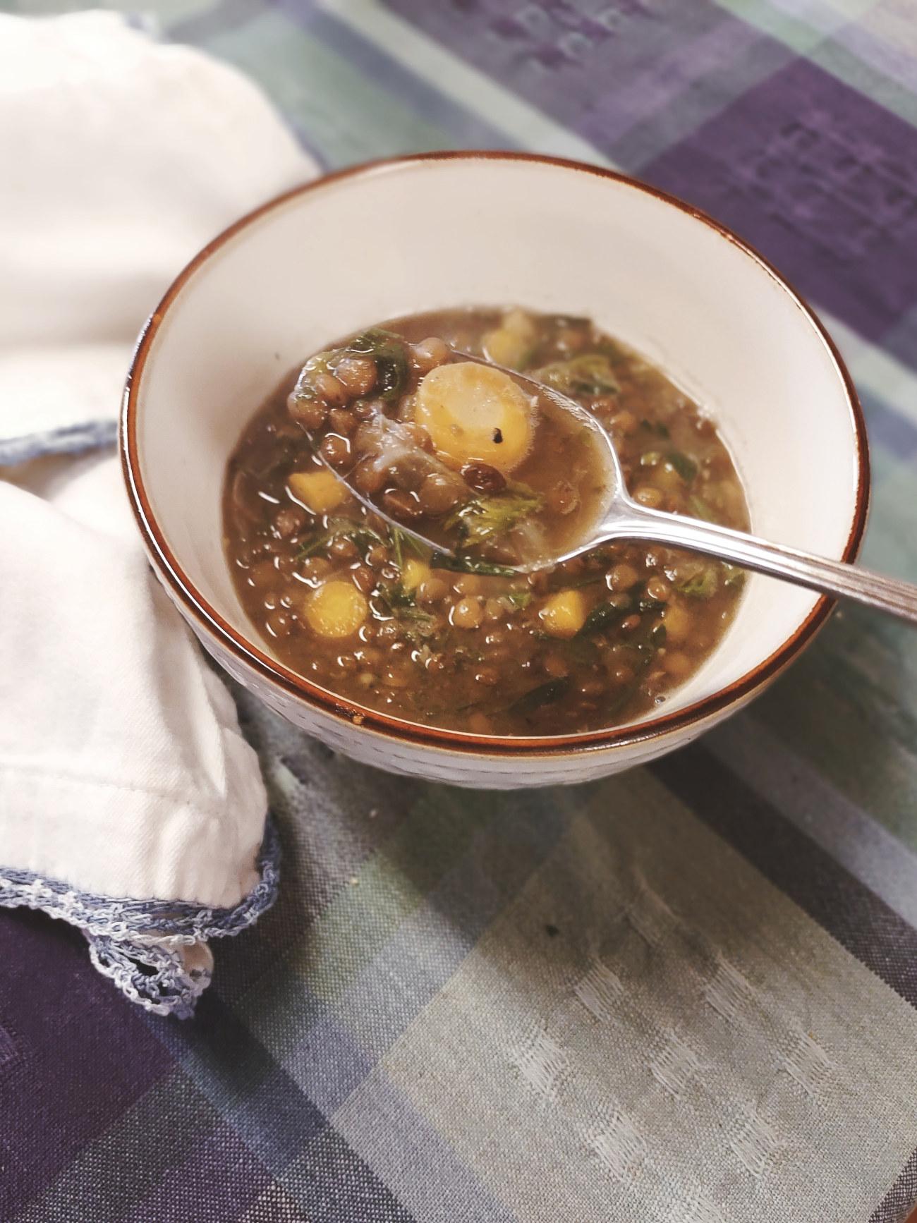 Woman enjoying a steaming bowl of lentil stew by a window on a rainy day, cozy atmosphere