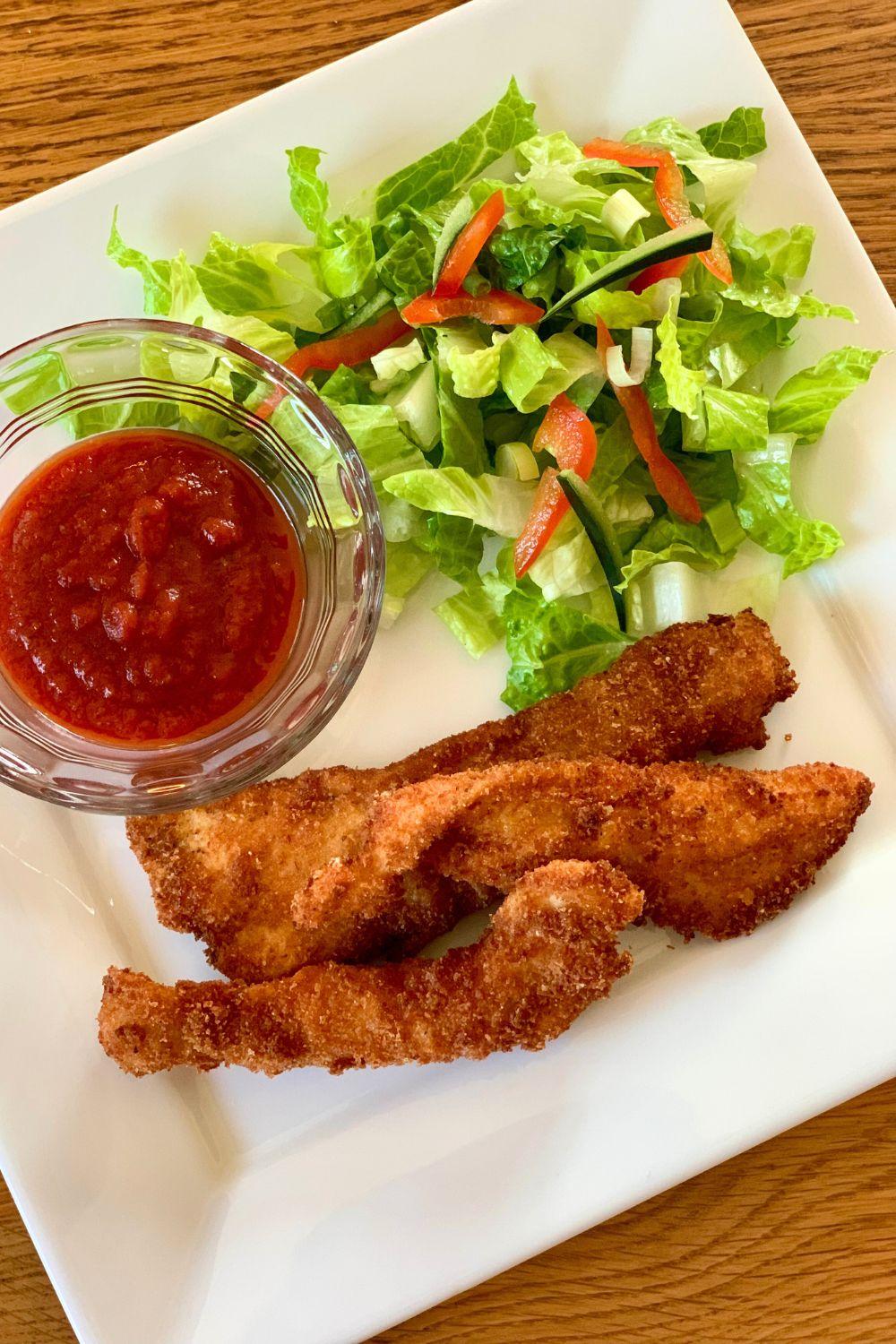 Fried chicken served on a plate with marinara dipping sauce