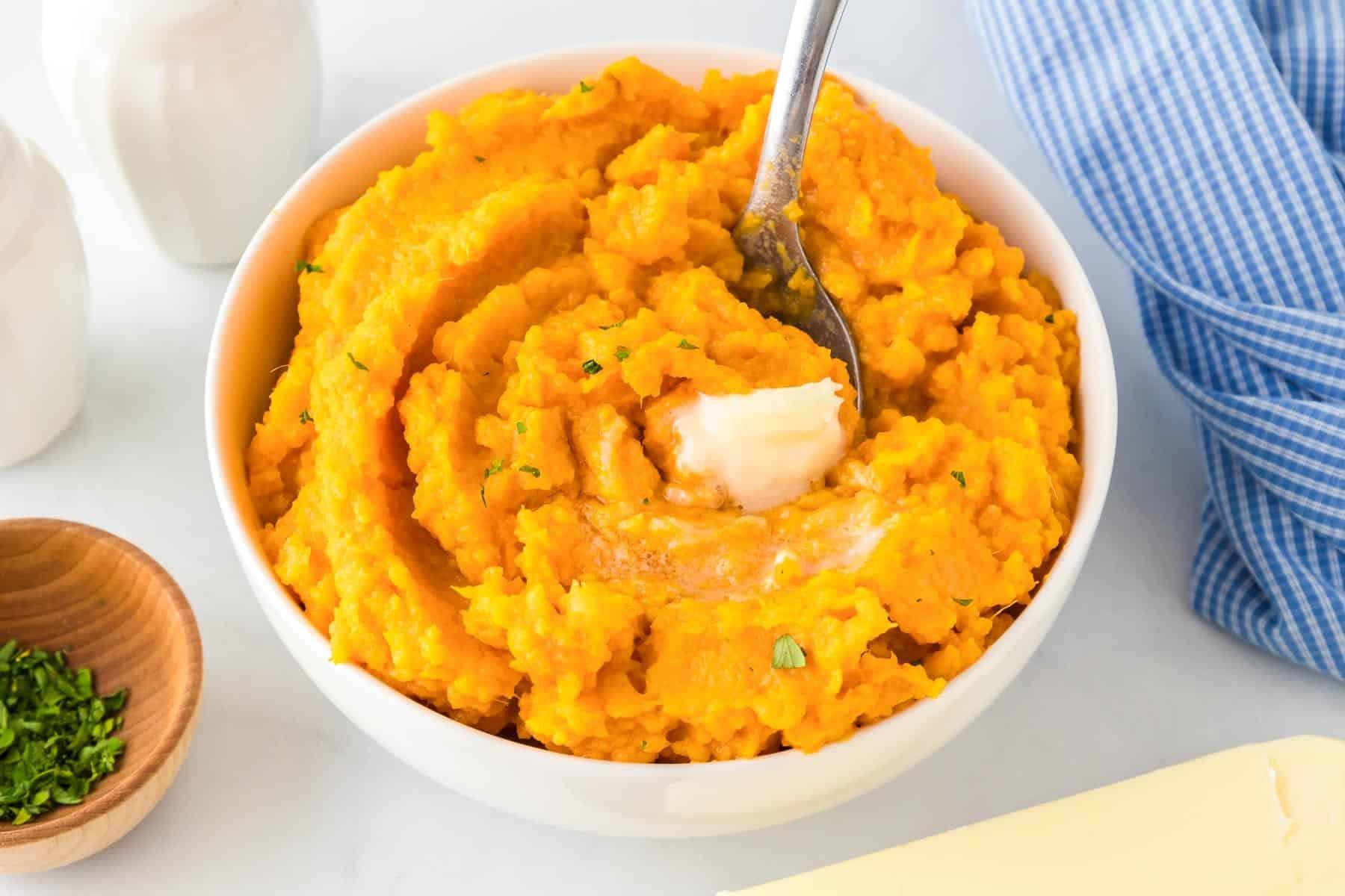 Close-up shot of creamy mashed sweet potatoes in a large mixing bowl