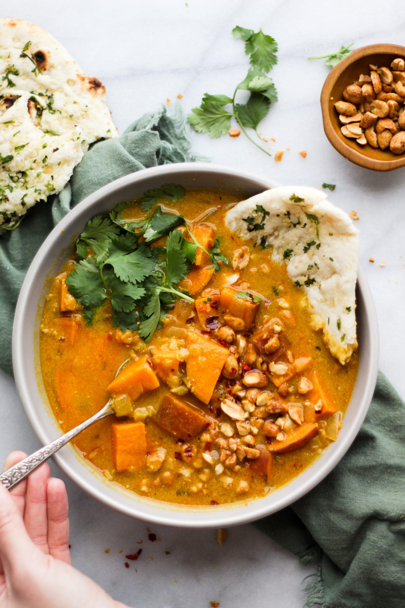 A hearty bowl of lentil soup with sweet potatoes, garnished with fresh herbs