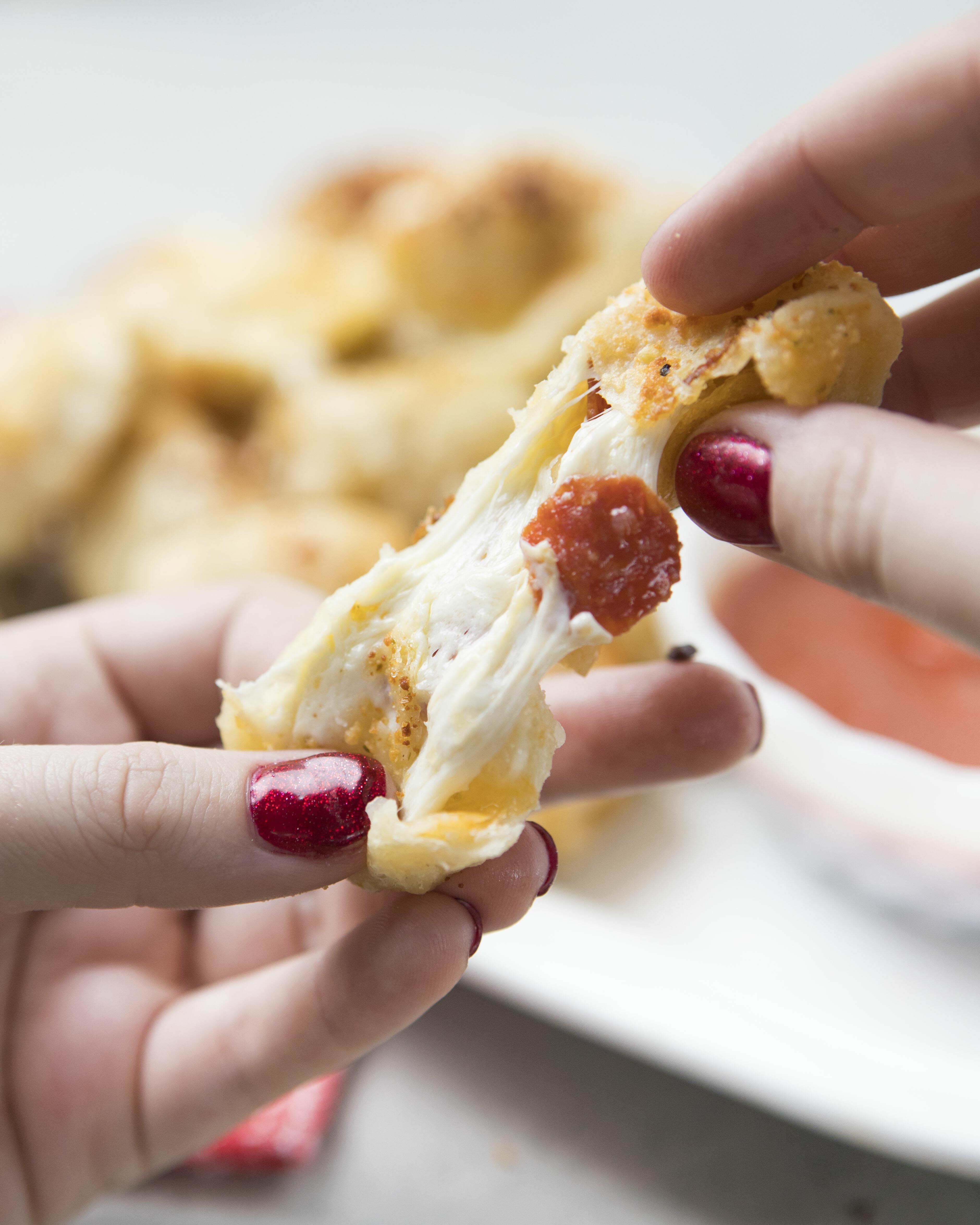 A close-up of a person taking a bite of a sheet pan pizza roll