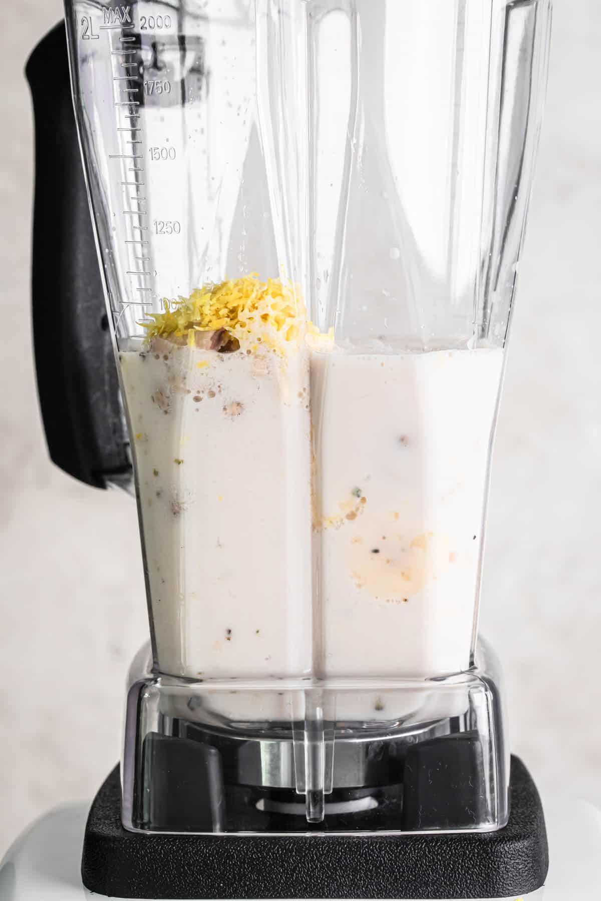 Close-up shot of a blender as ingredients are being blended together for a lemon almond smoothie