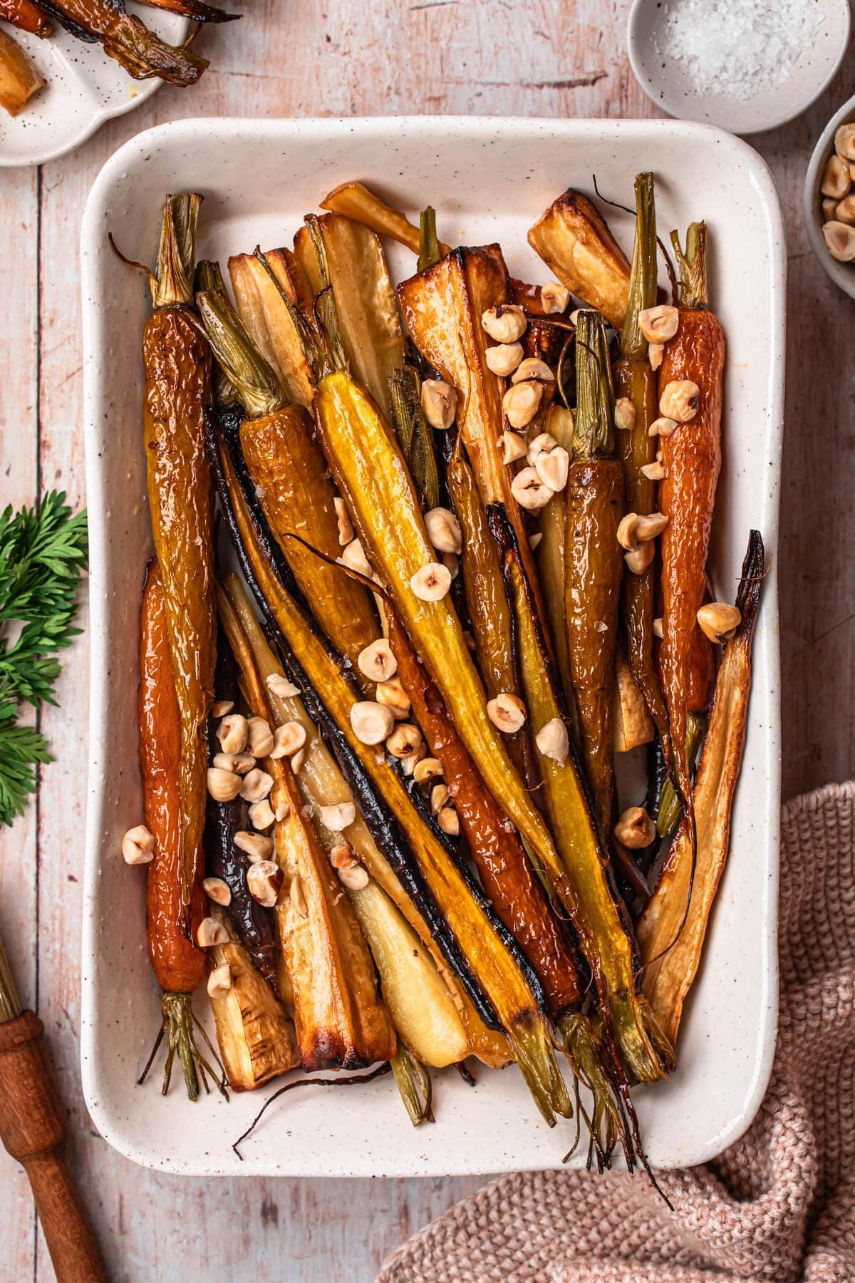 A rustic wooden table set with a bowl of roasted carrot and parsnip puree, crusty bread, and a glass of wine