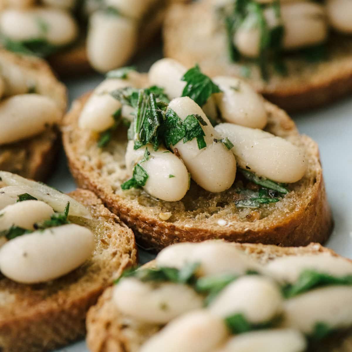Close-up shot of White Bean and Rosemary Bruschetta on a rustic wooden board