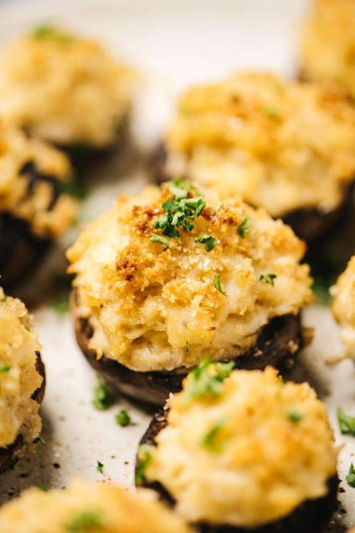 A platter of crab-stuffed mushrooms garnished with parsley and parmesan cheese