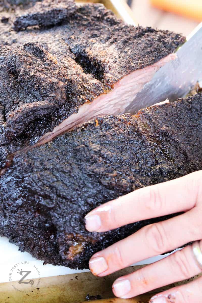 Close-up shot of hands shredding a smoked brisket