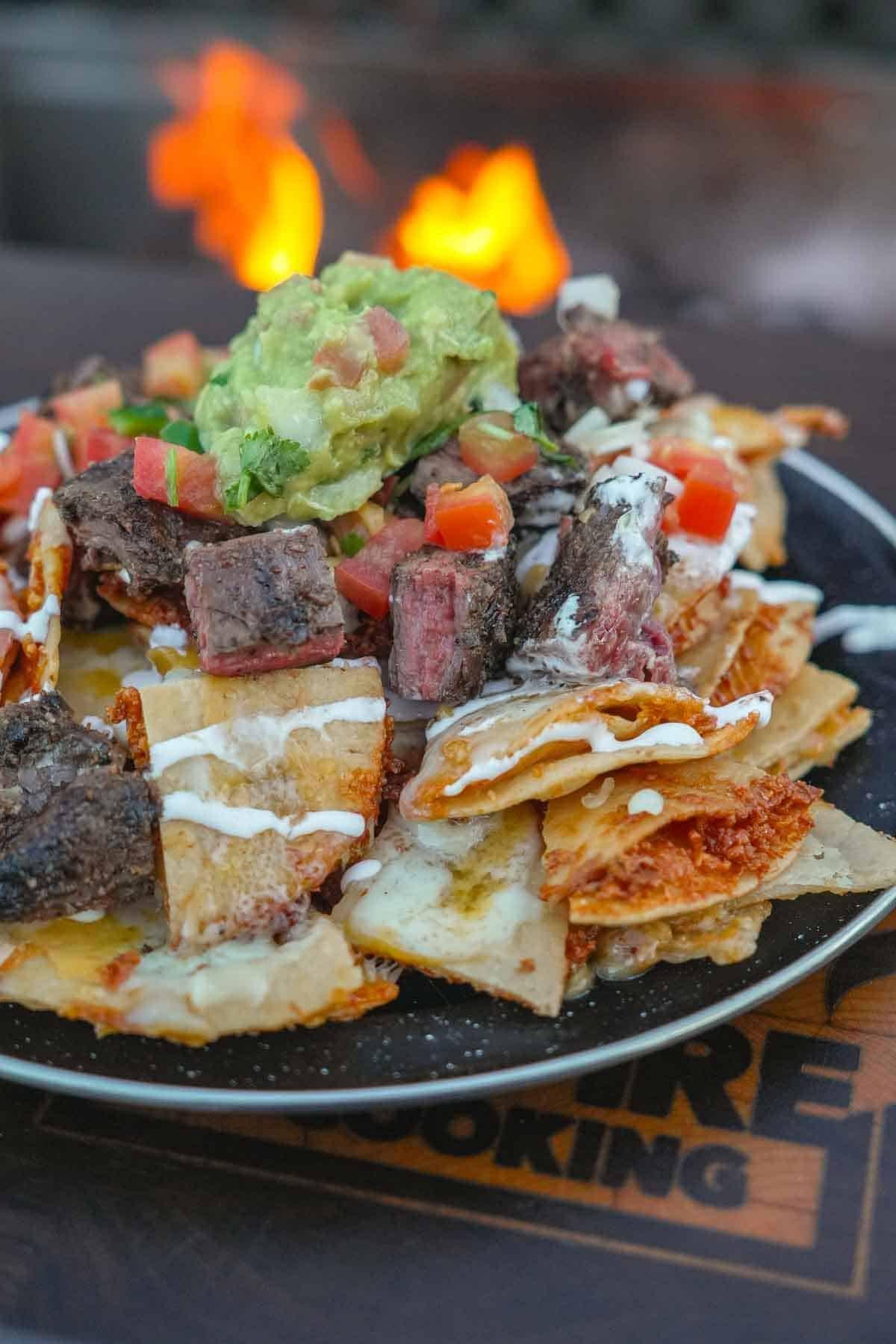 close-up of feijoada nachos with melted cheese and fresh toppings