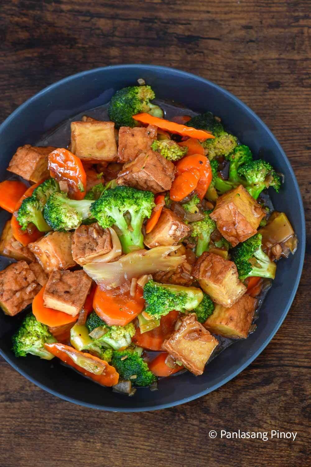 A person enjoying a plate of broccoli and tofu stir-fry