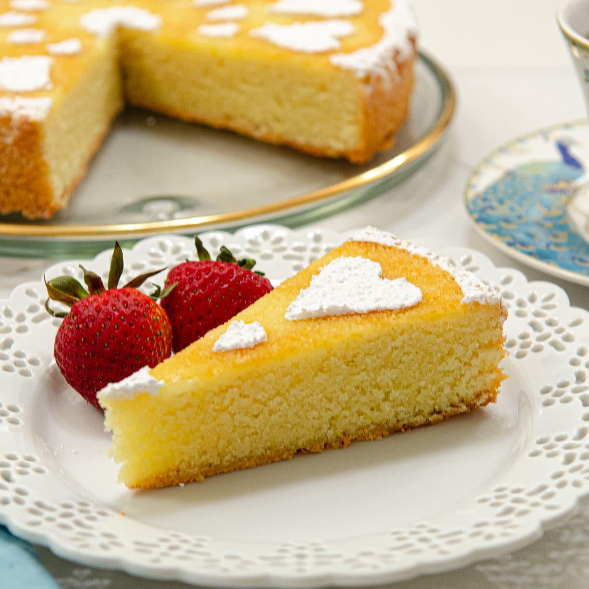 A person enjoying a slice of orange almond cake with a cup of coffee or tea