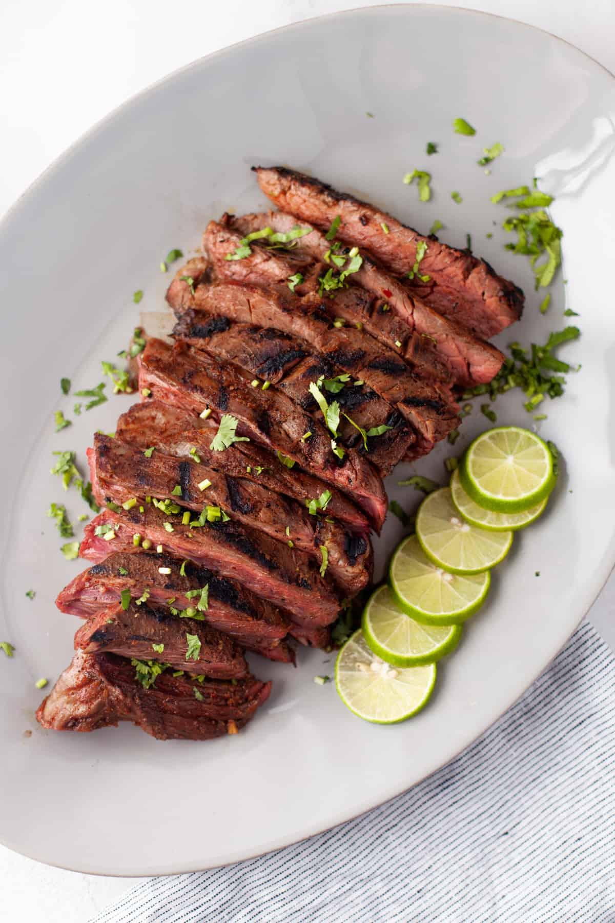 flank steak marinating in a bowl with lime juice and spices