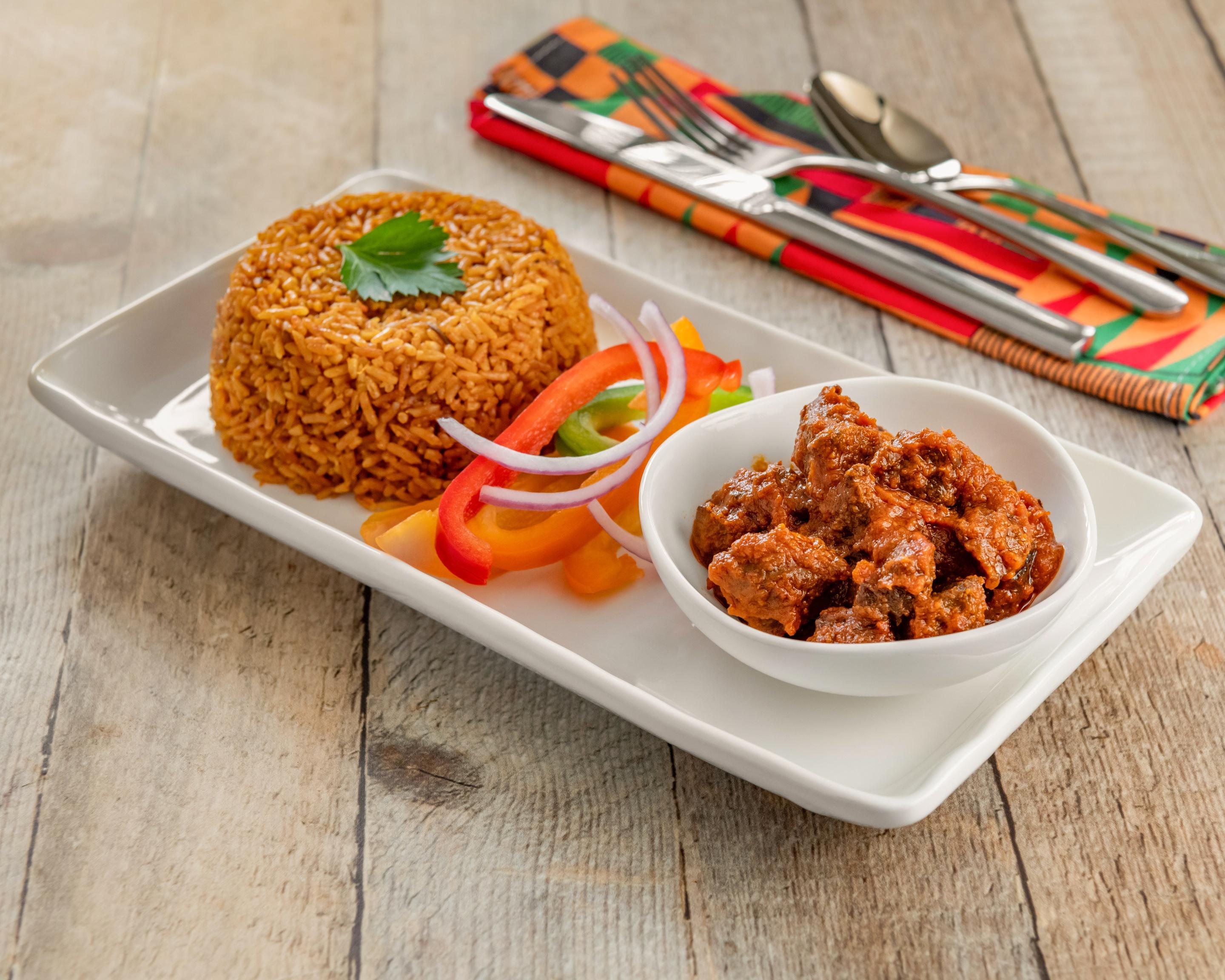 A vibrant photo of Jollof rice served alongside grilled shrimp skewers, garnished with fresh herbs