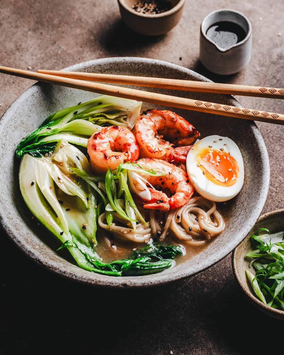 Overhead shot of a bowl of Sriracha Noodles with Shrimp and Bok Choy, garnished with sesame seeds and green onions