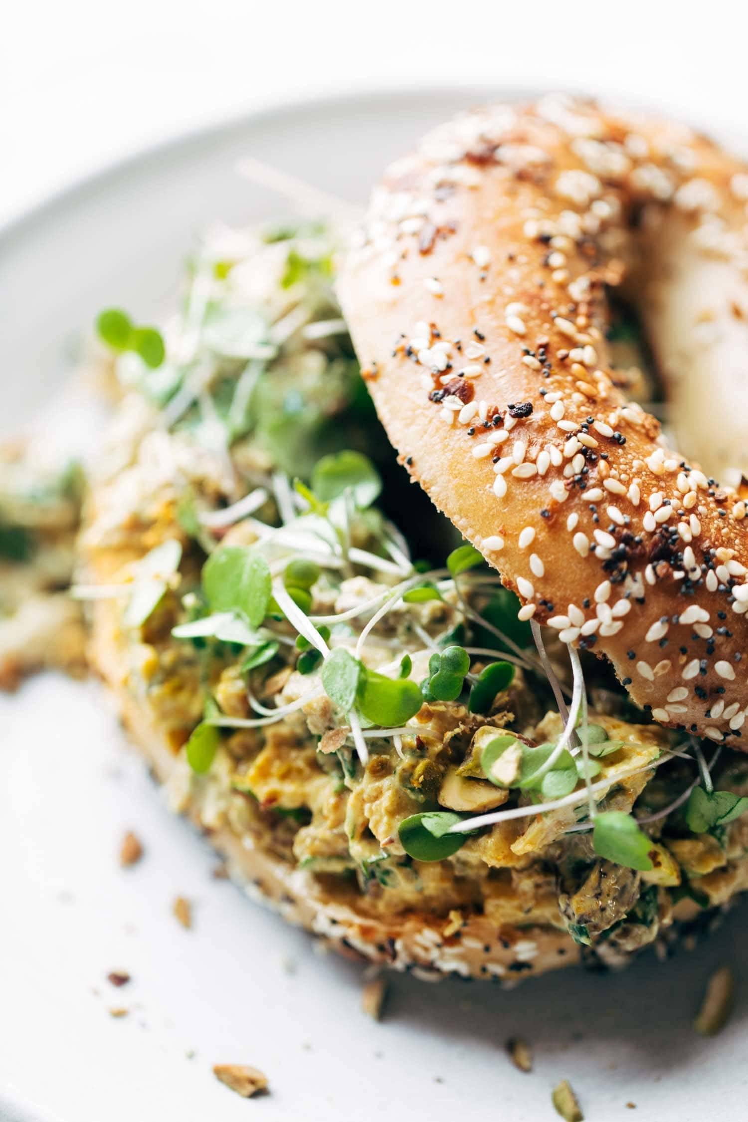 Close-up of a curried chicken salad bagel with cilantro garnish