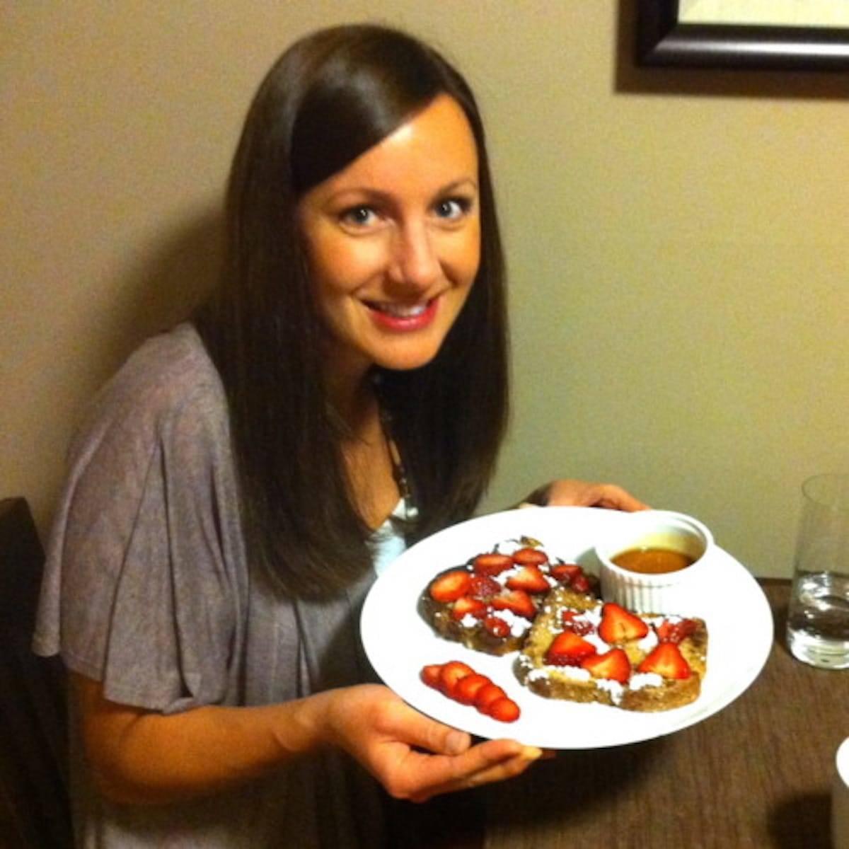A person holding a plate of French toast bites, smiling