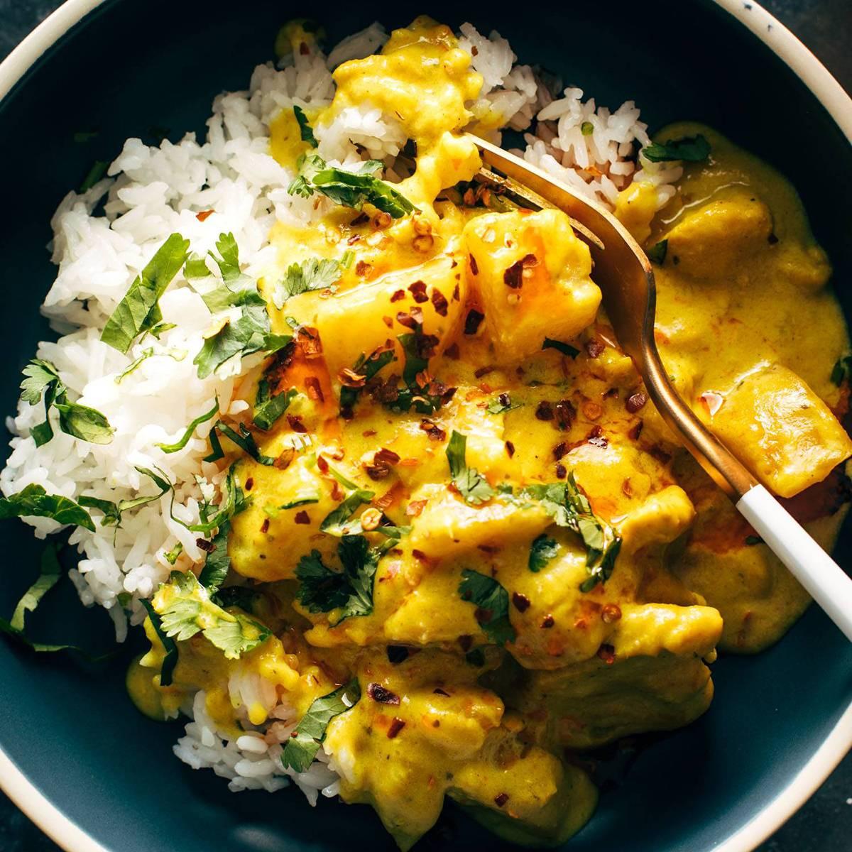 A person happily eating a bowl of yellow curry rice
