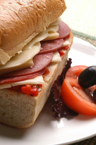 Close-up shot of a spicy Italian panini with provolone, oozing cheese, and visible salami and roasted red peppers.