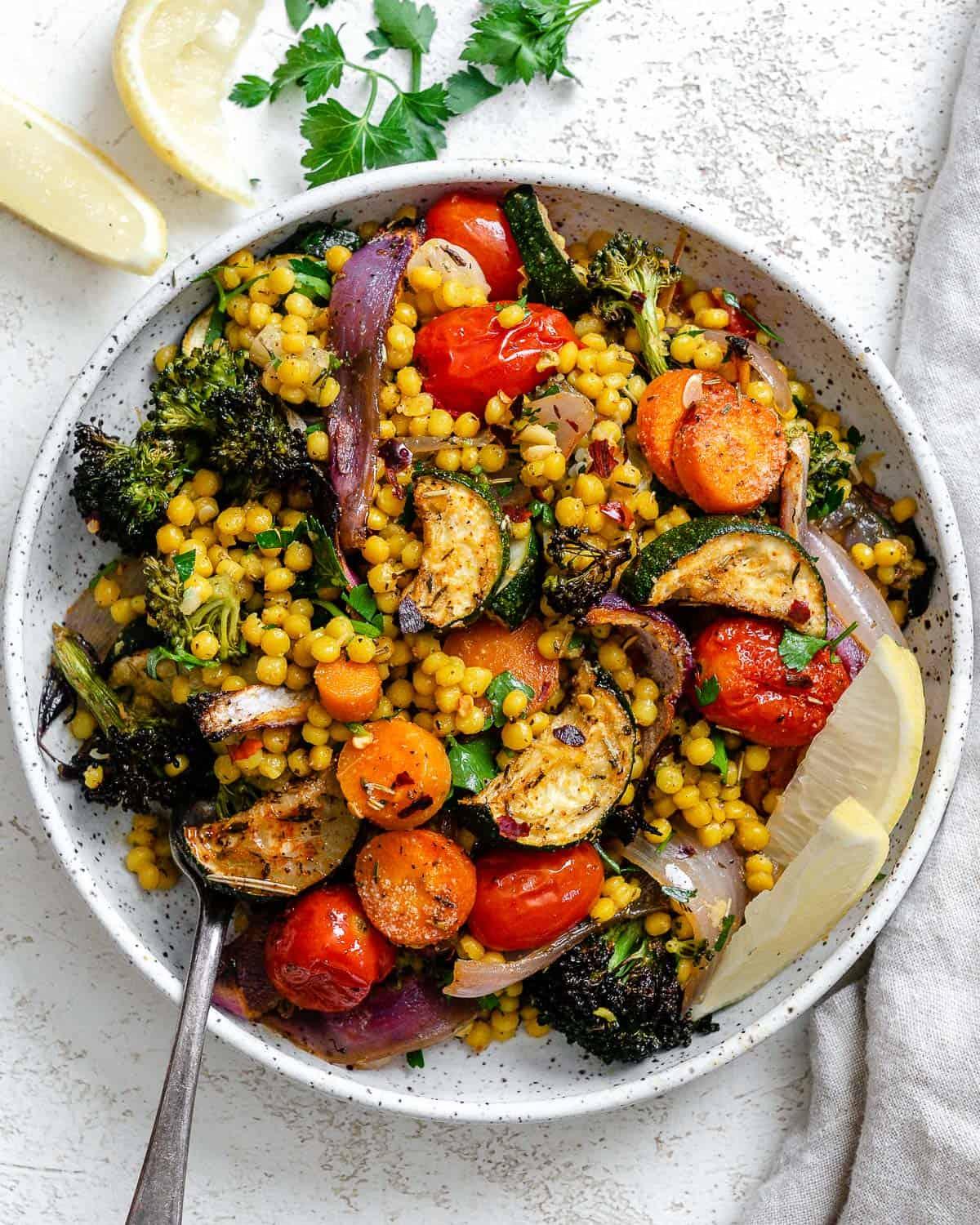 A finished bowl of Roasted Vegetable and Couscous Salad, garnished with fresh herbs