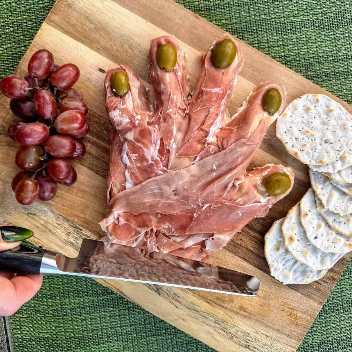 Close-up of a hand assembling apple prosciutto skewers