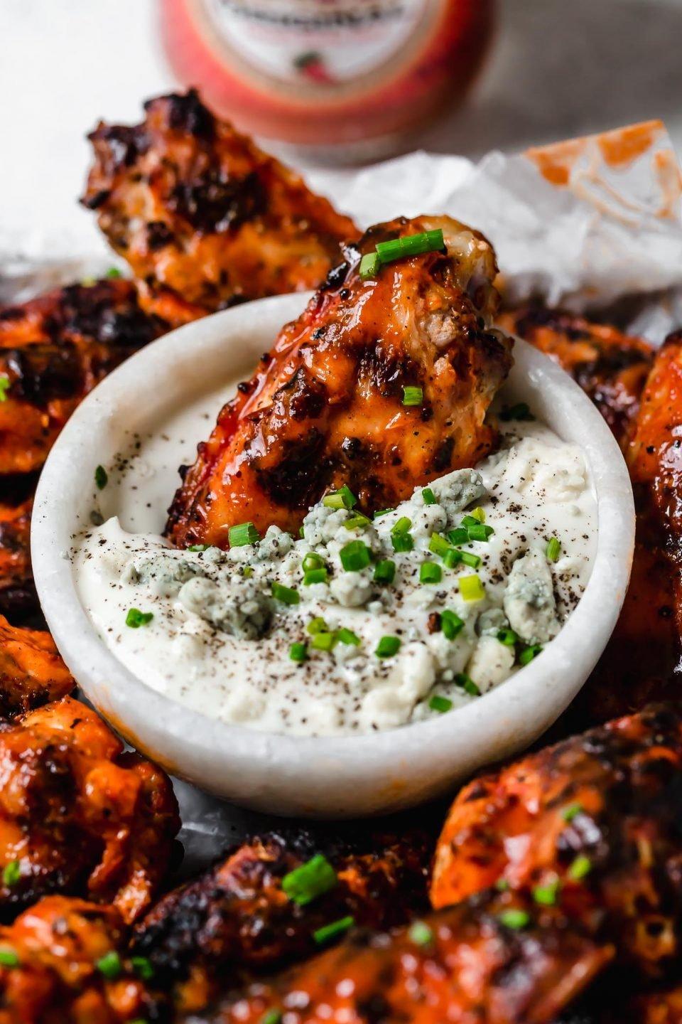 Close-up of perfectly grilled chicken wings with a side of creamy yogurt sauce
