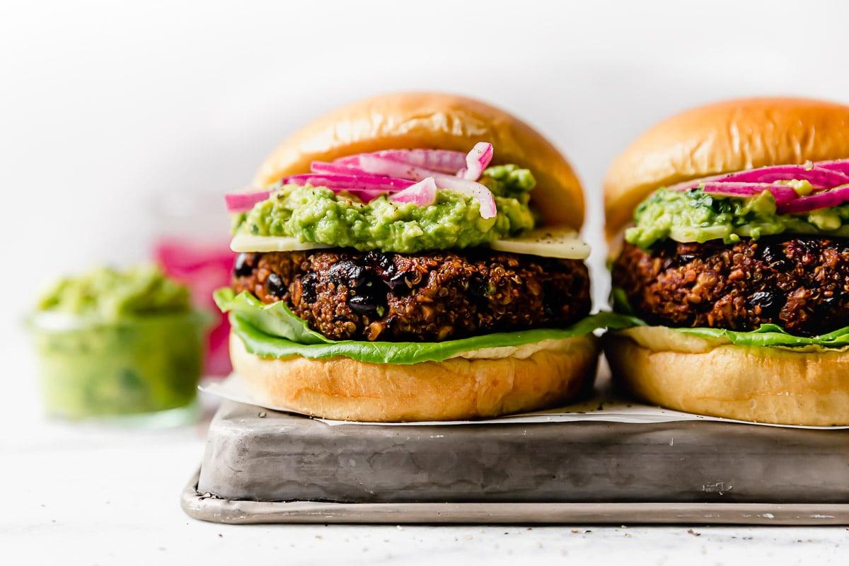 A platter of colorful grilled vegetable and black bean burgers, garnished with fresh herbs