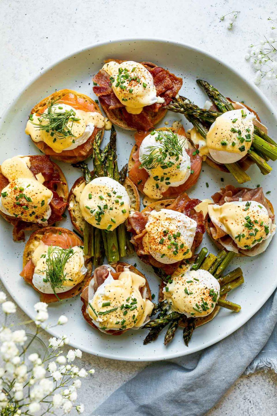 Overhead shot of a table setting with multiple plates of Eggs Benedict with Basil Hollandaise, along with mimosas and fresh fruit