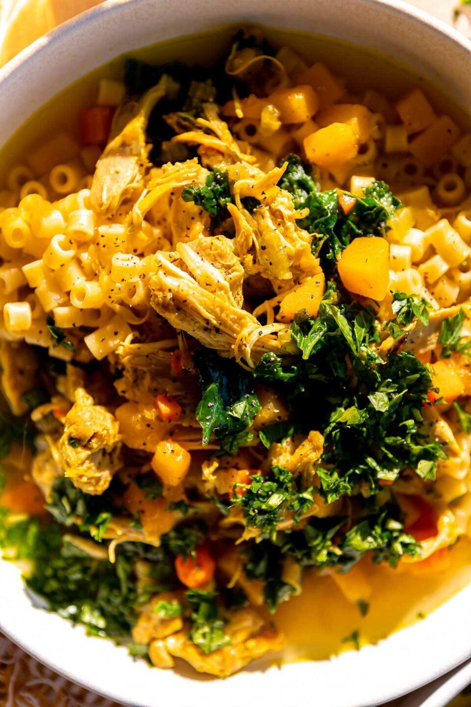 Close-up shot of a flavorful, golden-brown chicken broth in a clear bowl, garnished with fresh herbs.