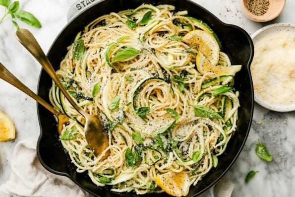 Close-up of gluten-free pasta with lemon garlic sauce and zucchini noodles, garnished with fresh herbs
