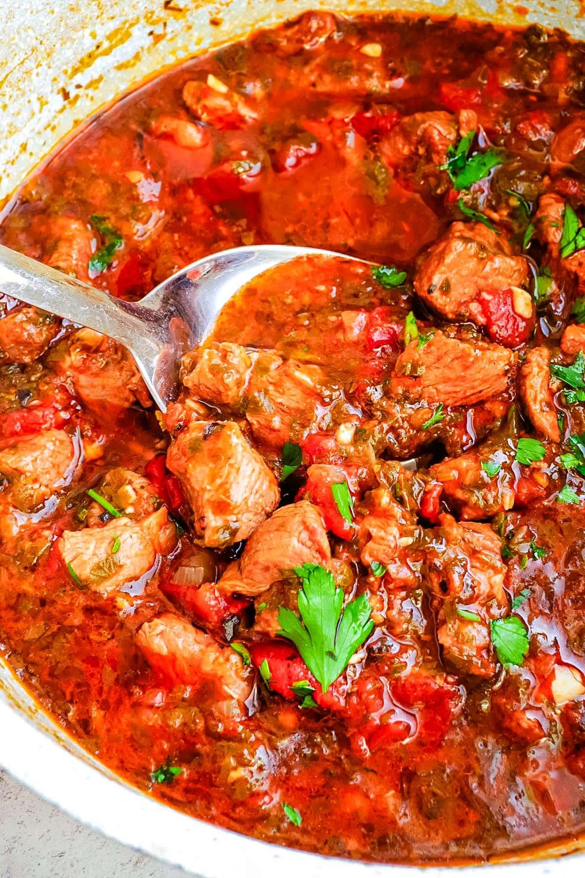 Close-up shot of a slow cooker filled with Mediterranean lamb stew, garnished with fresh herbs and lemon wedges