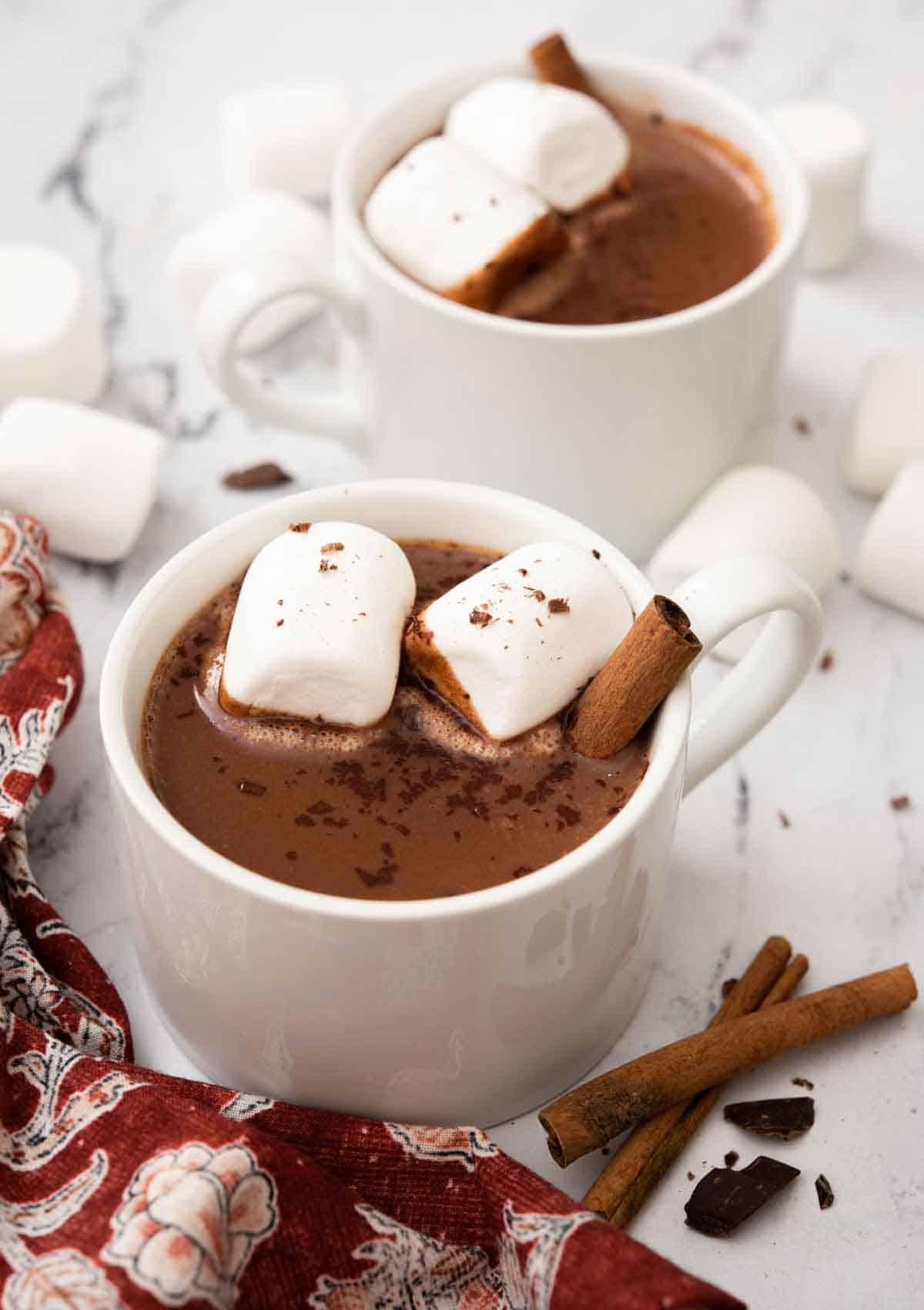 steaming mug of Mexican hot chocolate with cinnamon sticks and chili flakes