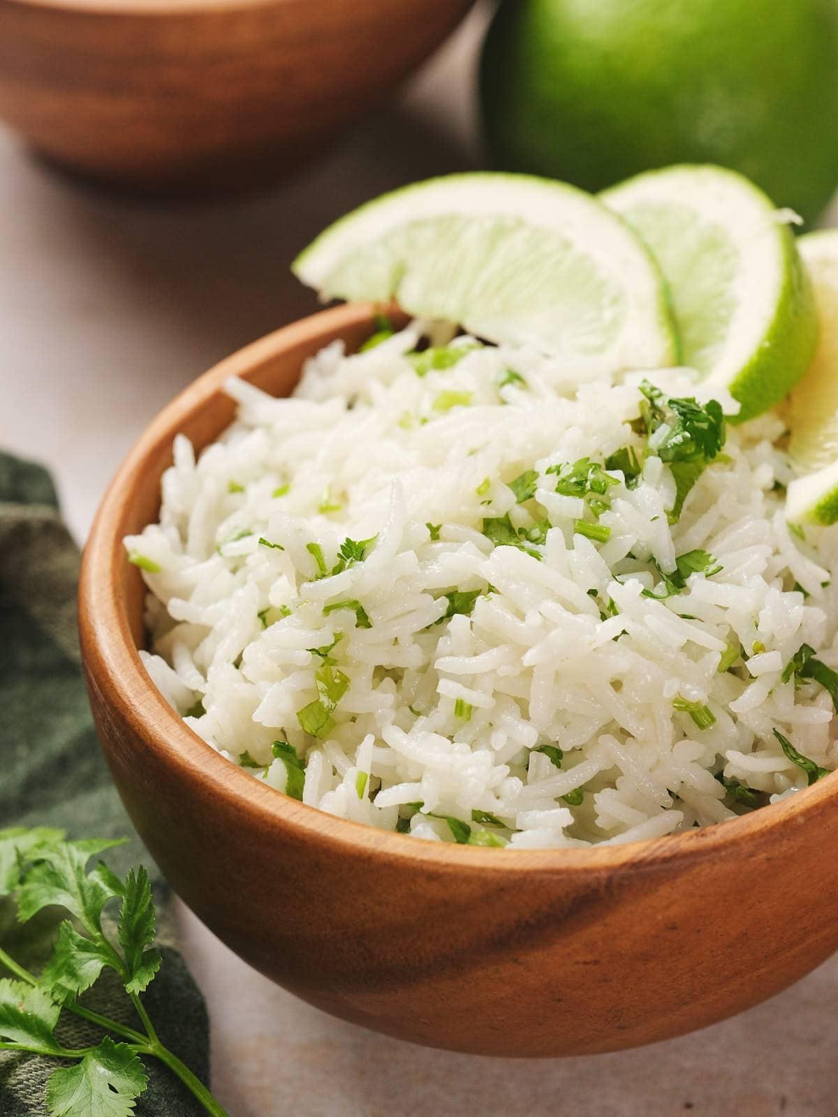 A vibrant bowl of lime cilantro rice garnished with fresh cilantro and lime wedges.