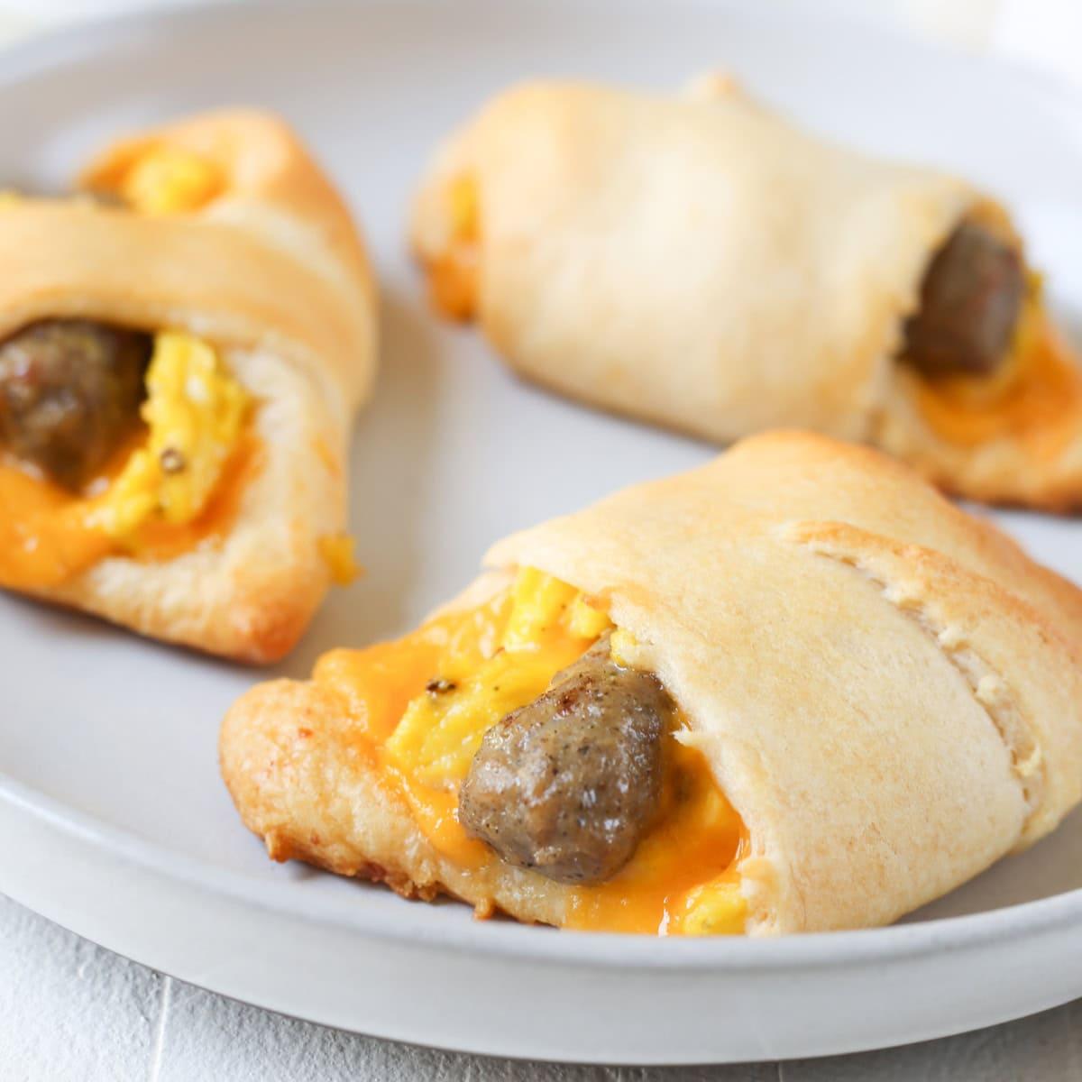 Close-up of golden crescent roll-ups with visible sausage and egg filling, garnished with parsley