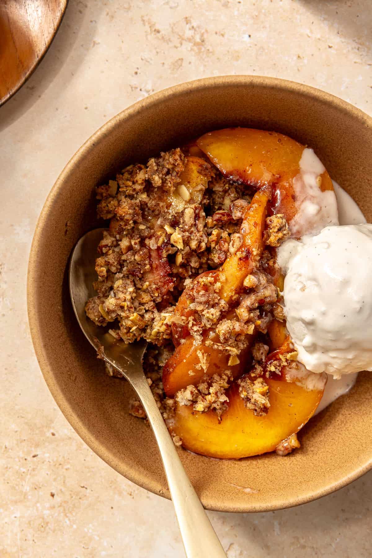 Close-up of a slice of Paleo Peach Cobbler, showing the texture of both the crumble and the peaches.
