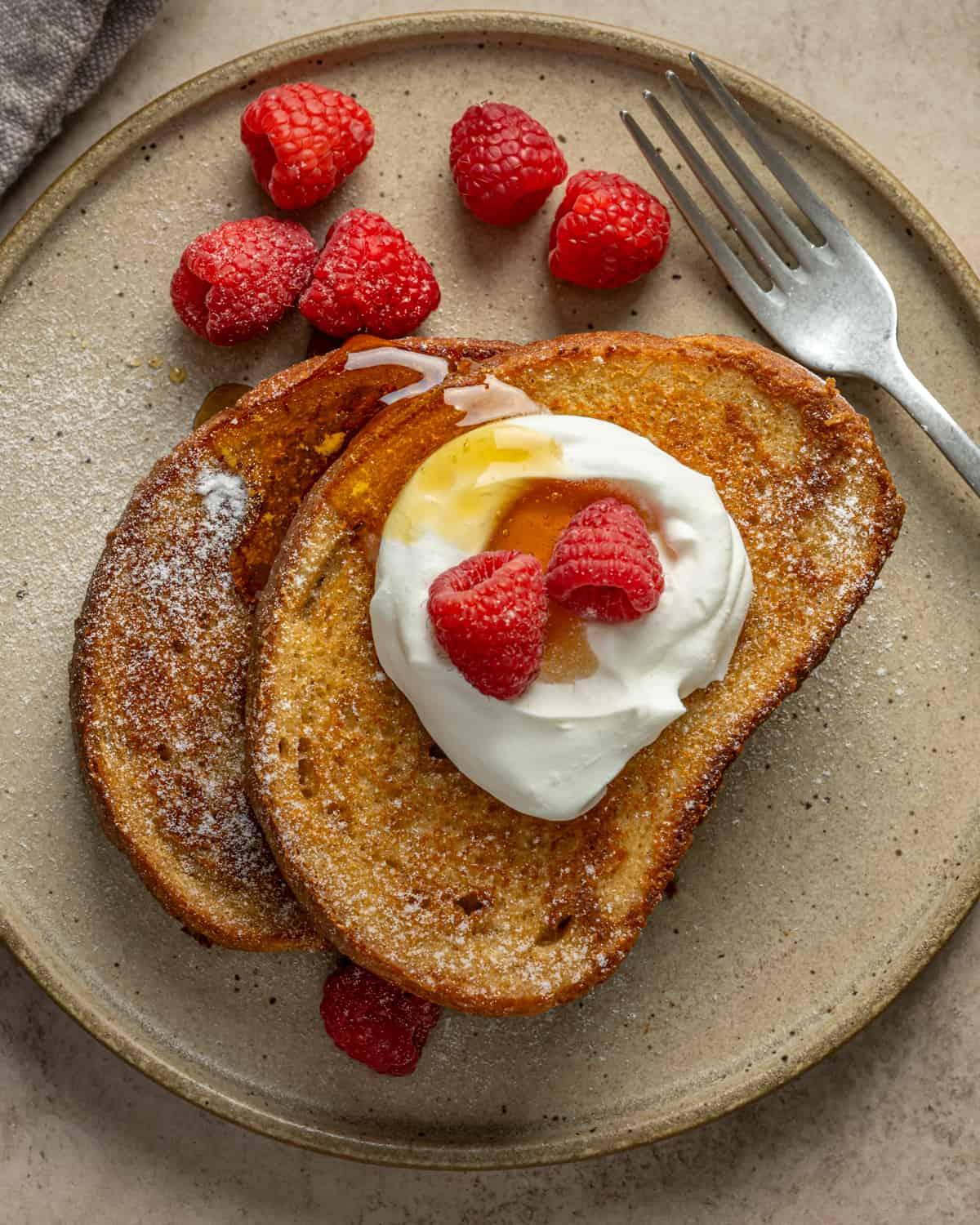A plate of delicious-looking vegan French toast, with various toppings such as fruit and syrup.