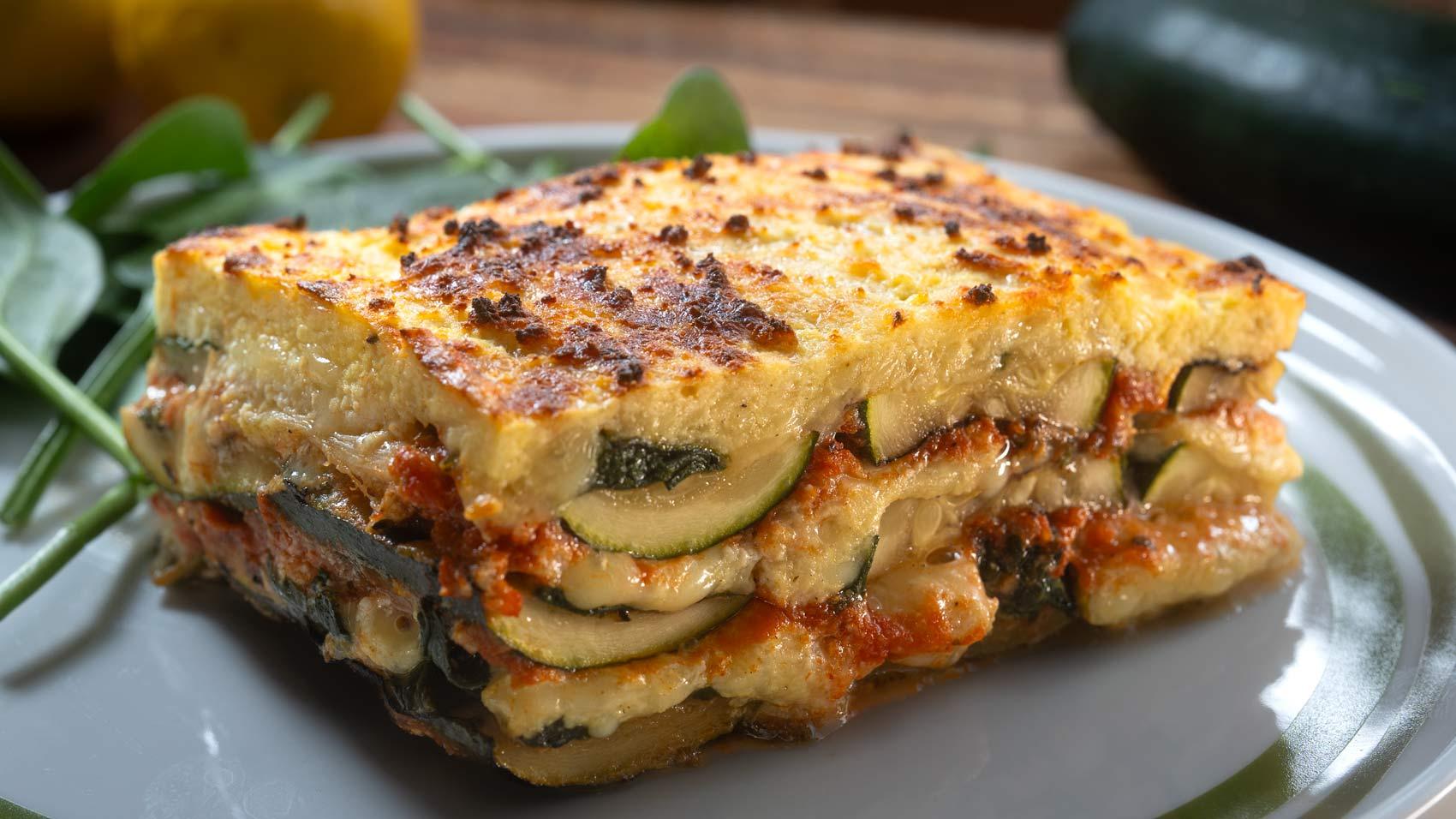 A beautiful, golden-brown Gourmet Zucchini Lasagna, freshly baked, with a sprinkle of Parmesan cheese, in a rustic setting.