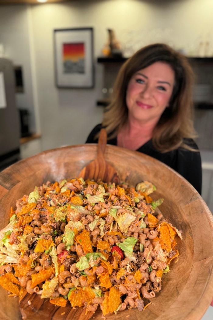 A person enjoying a bowl of taco salad with a big smile