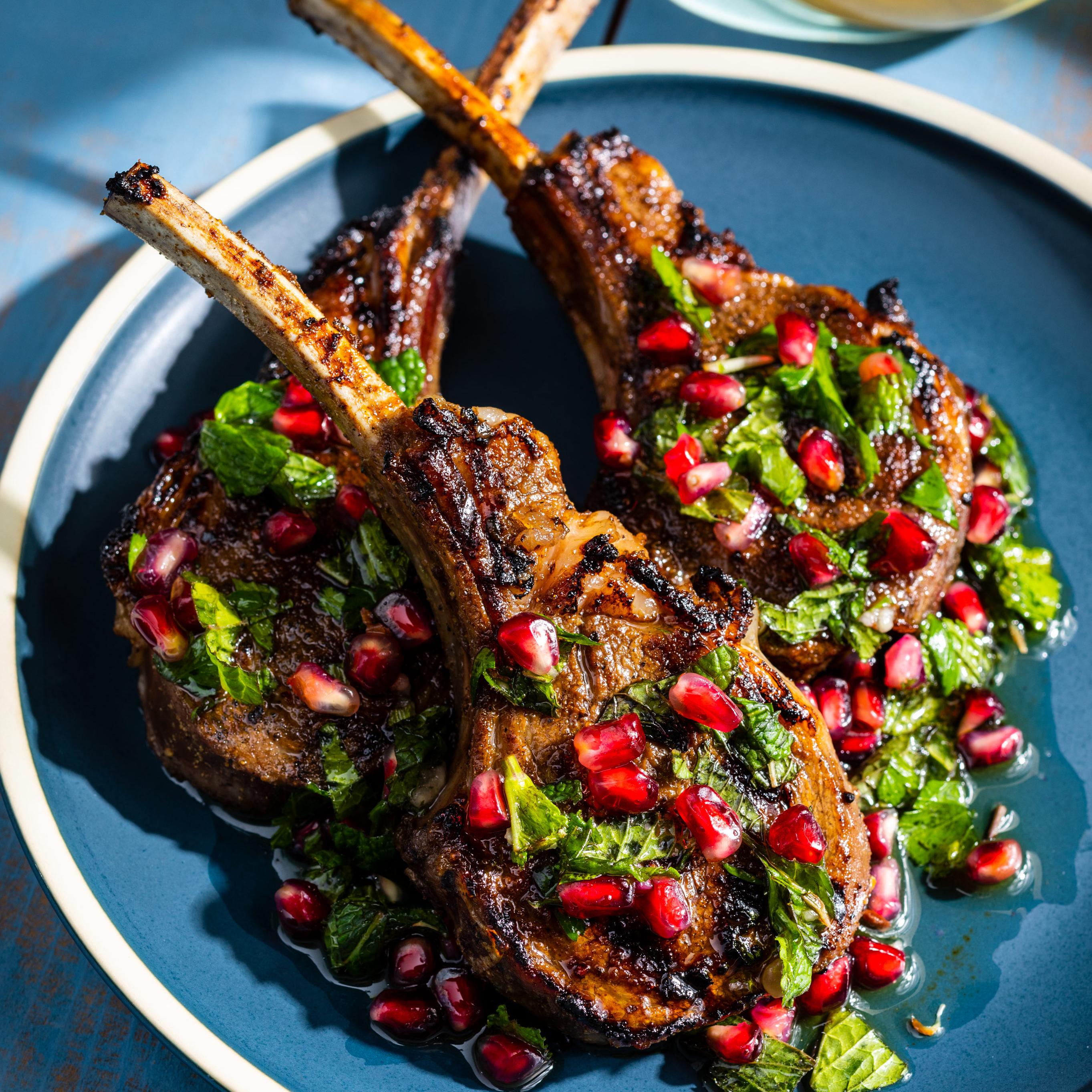close-up shot of pomegranate-glazed lamb chops being brushed with glaze in a skillet