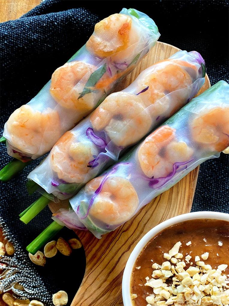 Close-up shot of vibrant Thai chicken spring rolls with a peanut-chili dipping sauce