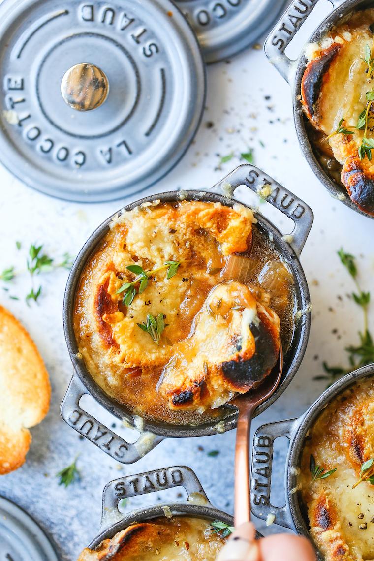 A rustic bowl of Federalist French onion soup, with melted cheese bubbling on top, garnished with fresh thyme.