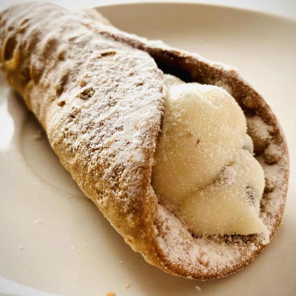 Close-up shot of golden-brown Coastal Crullers dusted with powdered sugar, arranged on a white platter