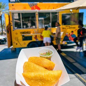 Image of a bustling Medellin street scene with empanadas in the foreground