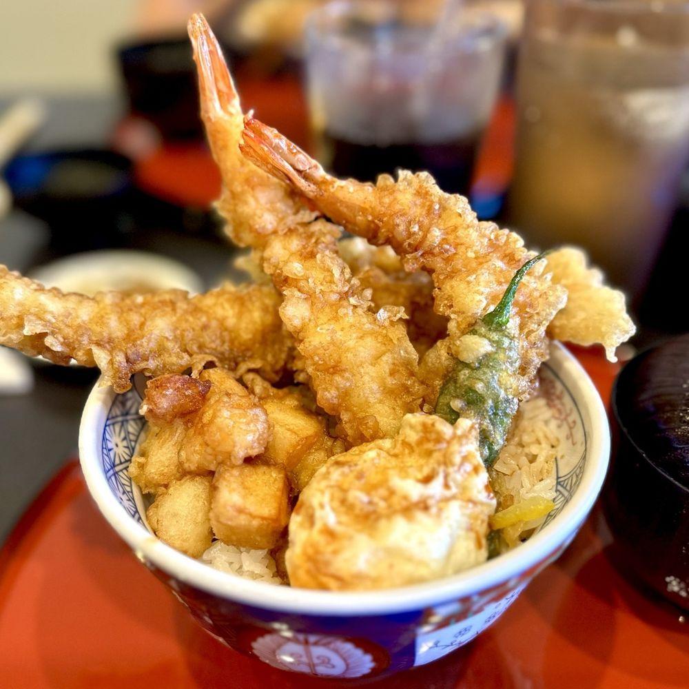 A hand drizzling honey over a plate of calamansi tempura